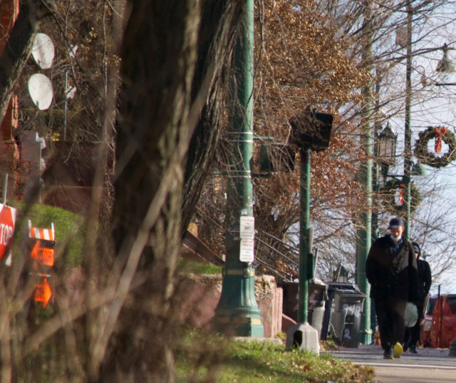 Men in winter clothes walking on Park Street sidewalk. One has mask around chin. 