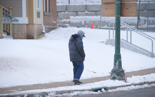 Person wearing mask and winter coat walking