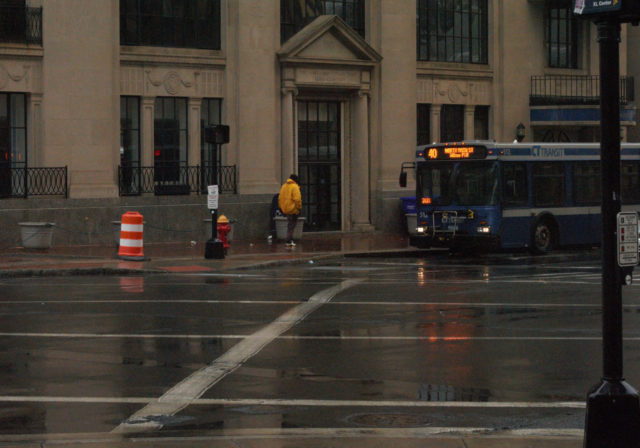 Person walking near bus in rain
