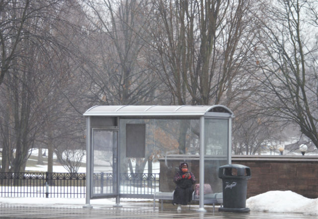 Woman sitting in bus shelter during rain storm