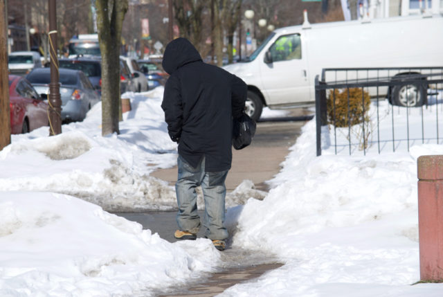 Man carefully walking across icy sidewalk