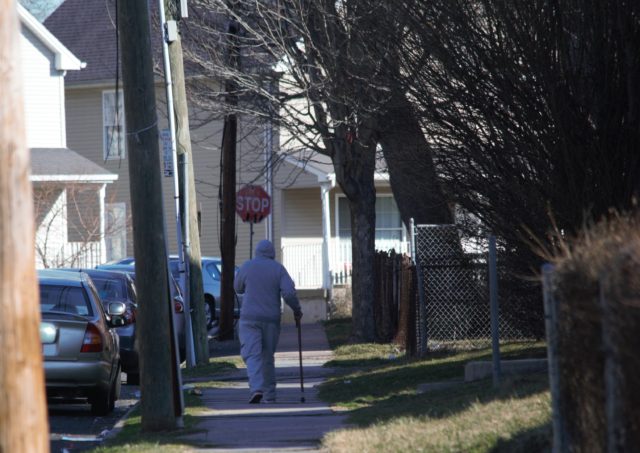 Person walking down street using cane