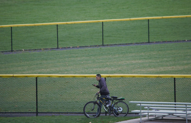Person with bicycle next to baseball field