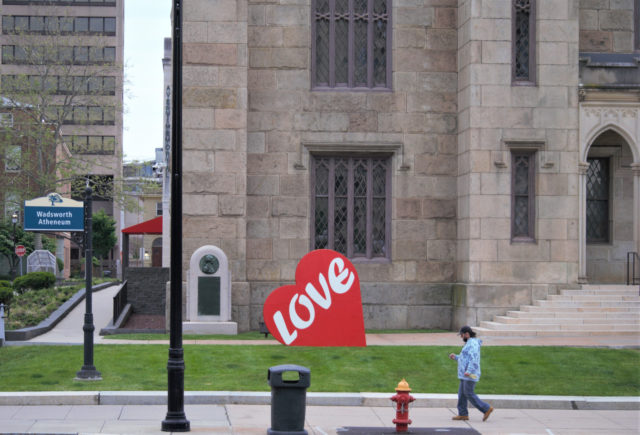 Person walking by giant heart that reads "love" 