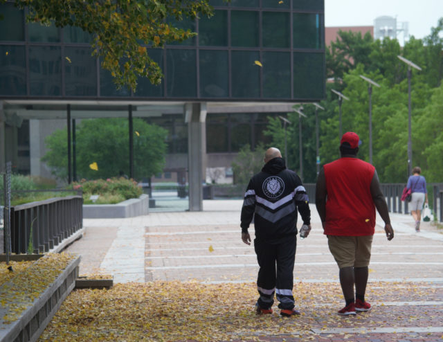 People walking on Constitution Plaza as leaves fall in July